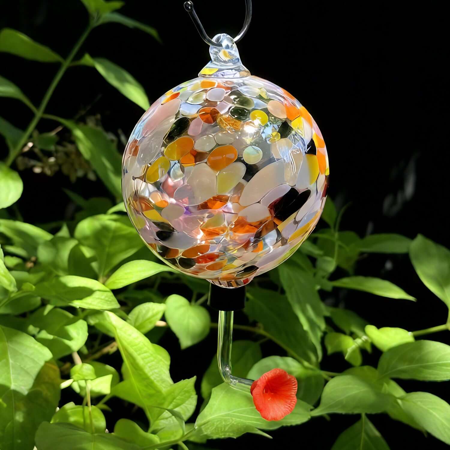 Be the Unicorn colorful glass garden ornament surrounded by green foliage, adding sparkle to outdoor spaces.