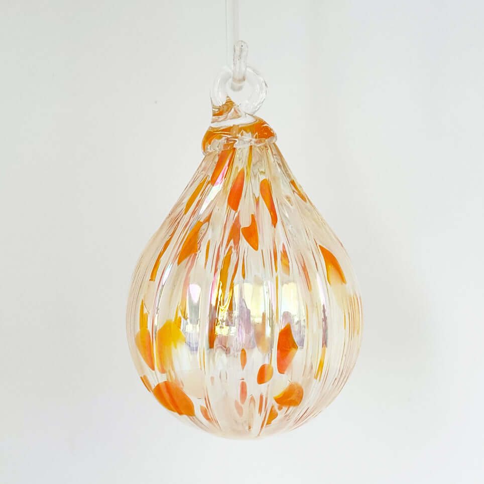 Handcrafted glass ornament in Salmonberry color, featuring vibrant orange speckles and unique patterns.