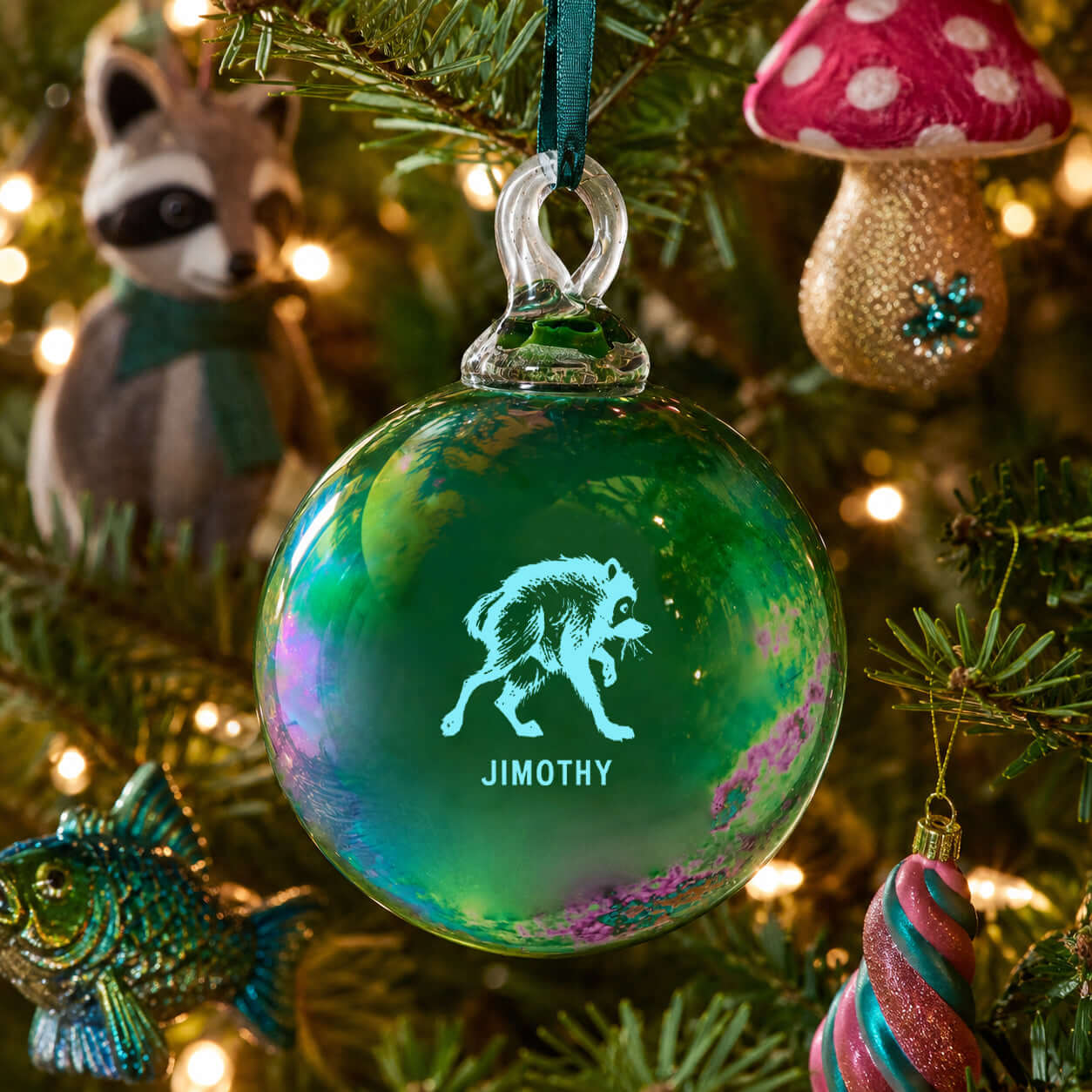 Glass ornament featuring Jimothy, the city's favorite dumpster king, hanging on a festive tree.
