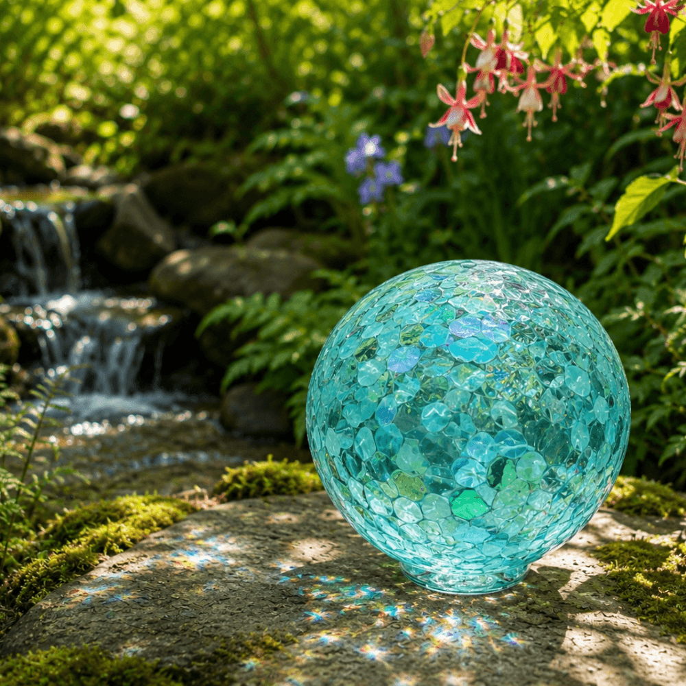 Whidbey decorative glass sphere with aqua tones in a serene garden setting, reflecting sunlight.